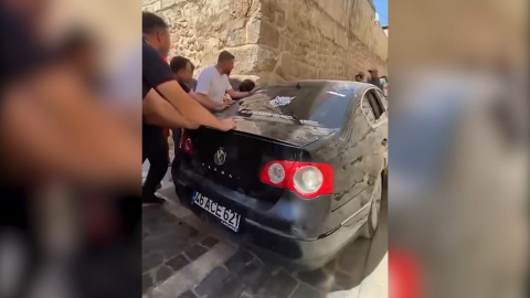 Dar sokakta sıkışan otomobil güçlükle çıkarıldı